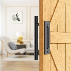 an open wooden door with a black handle on it and a living room in the background