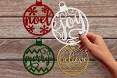 hand holding up three christmas ornament cutouts on top of a wooden table