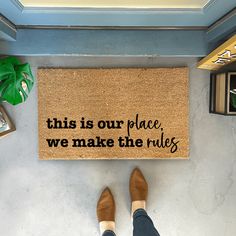 a person standing in front of a door mat that says, this is our place we make the rules