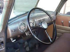 the interior of an old car with steering wheel and dashboard