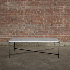 a white coffee table sitting in front of a brick wall with no one around it