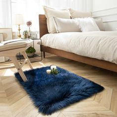 a bed room with a neatly made bed and a blue round rug on the floor