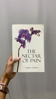 a person holding up a book about the nectar of pain