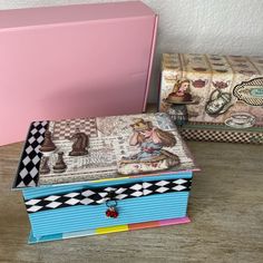 two boxes are sitting next to each other on the table, one is pink and the other is blue