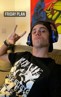 a man sitting on a couch wearing headphones and making the peace sign with his fingers