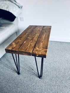 a wooden table sitting on top of a carpeted floor next to a white couch