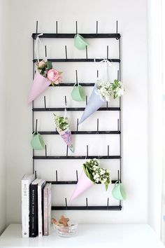 a shelf with some flowers on it next to a book and bookshelf in the corner