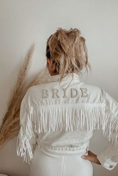 the back of a woman's jacket that says bride with fringes on it