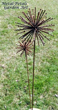 a metal plant sitting on top of a grass covered field with the words metal petals garden art