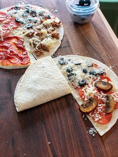 three different types of pizza sitting on top of a wooden table