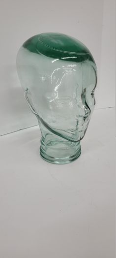 a green glass vase sitting on top of a white table