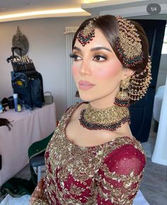 a woman in a red and gold dress with jewelry on her head, looking at the camera