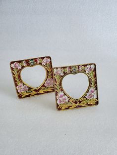 pair of heart shaped earrings with pink flowers and gold trimmings on white background