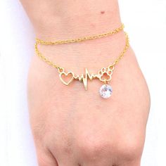 a person wearing a gold bracelet with a heart and heartbeat on it