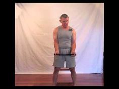 a man standing on top of a wooden floor holding a pair of dumbbells