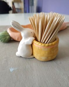 a white rabbit figurine sitting next to a toothbrush holder on a table