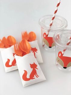 two cups with orange straws in them and some foxes on the napkins next to each other