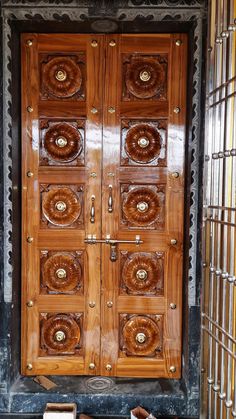 a pair of shoes sitting on the ground in front of a wooden door with intricate carvings