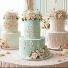 three tiered wedding cakes with flowers on them sitting on a table in front of a window