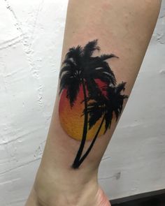 a small palm tree tattoo on the right inner arm and lower arm, with an orange sunset in the background