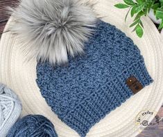 a blue and white knitted hat sitting on top of a table next to yarn balls