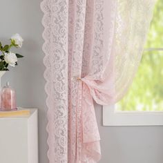 a pink curtain with lace on it in front of a white dresser and window sill