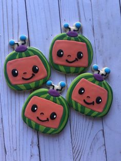 four decorated cookies sitting on top of a wooden table