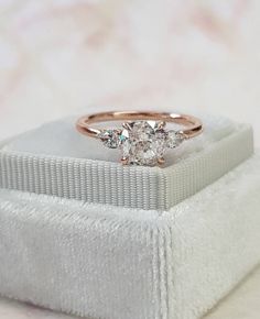 a three stone diamond ring sitting on top of a white box