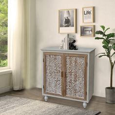 a white and grey cabinet sitting in front of a window next to a potted plant