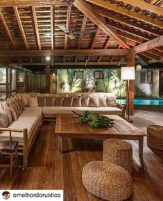 a living room filled with lots of furniture next to a swimming pool on top of a wooden floor