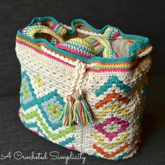 a multicolored crocheted bag with tassels on the handles and sides