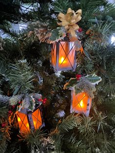 three lit lanterns hanging from a christmas tree