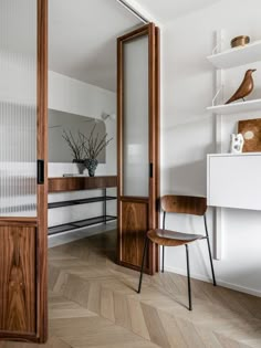 a wooden chair sitting in front of a mirror on top of a white wall next to a shelf