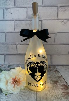 a bottle that has some lights in it and a flower on the table next to it