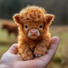 a hand holding a tiny brown and white cow