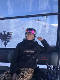 a woman sitting in the back of a ski lift with her arms up and smiling