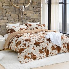 a cow print comforter set in front of a stone wall