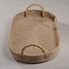 a woven basket with wooden handles on a gray surface