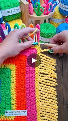 two hands are working on a colorful crochet project