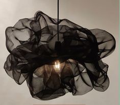 a light that is hanging from the ceiling with some black fabric on top of it