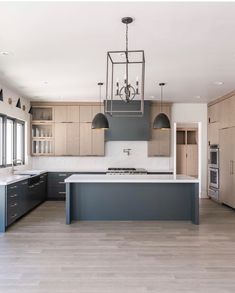 a large kitchen with an island in the middle and two pendant lights hanging from the ceiling