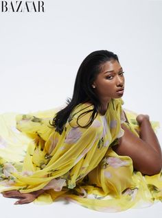 a woman sitting on the ground wearing a yellow dress