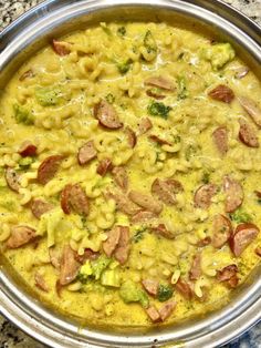 a pan filled with macaroni, broccoli and sausage in yellow sauce