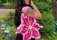 a woman with long hair wearing a pink crochet bag and talking on her cell phone