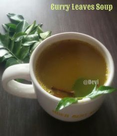 there is a cup of tea with leaves on the table next to it and another cup in the background