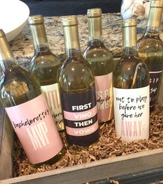 six bottles of wine in a box on a counter top, with the names first and then printed on them