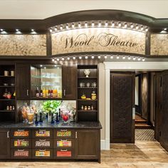 the wood theatre bar has many bottles and glasses on it's display shelves, along with an assortment of drinks