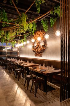 an empty restaurant with wooden tables and hanging plants on the wall, along with chairs