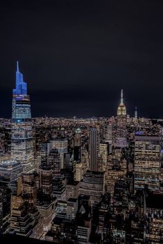 an aerial view of new york city at night with the empire building lit up in blue