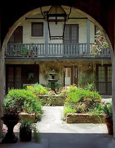 an archway leading into a building with plants and potted plants